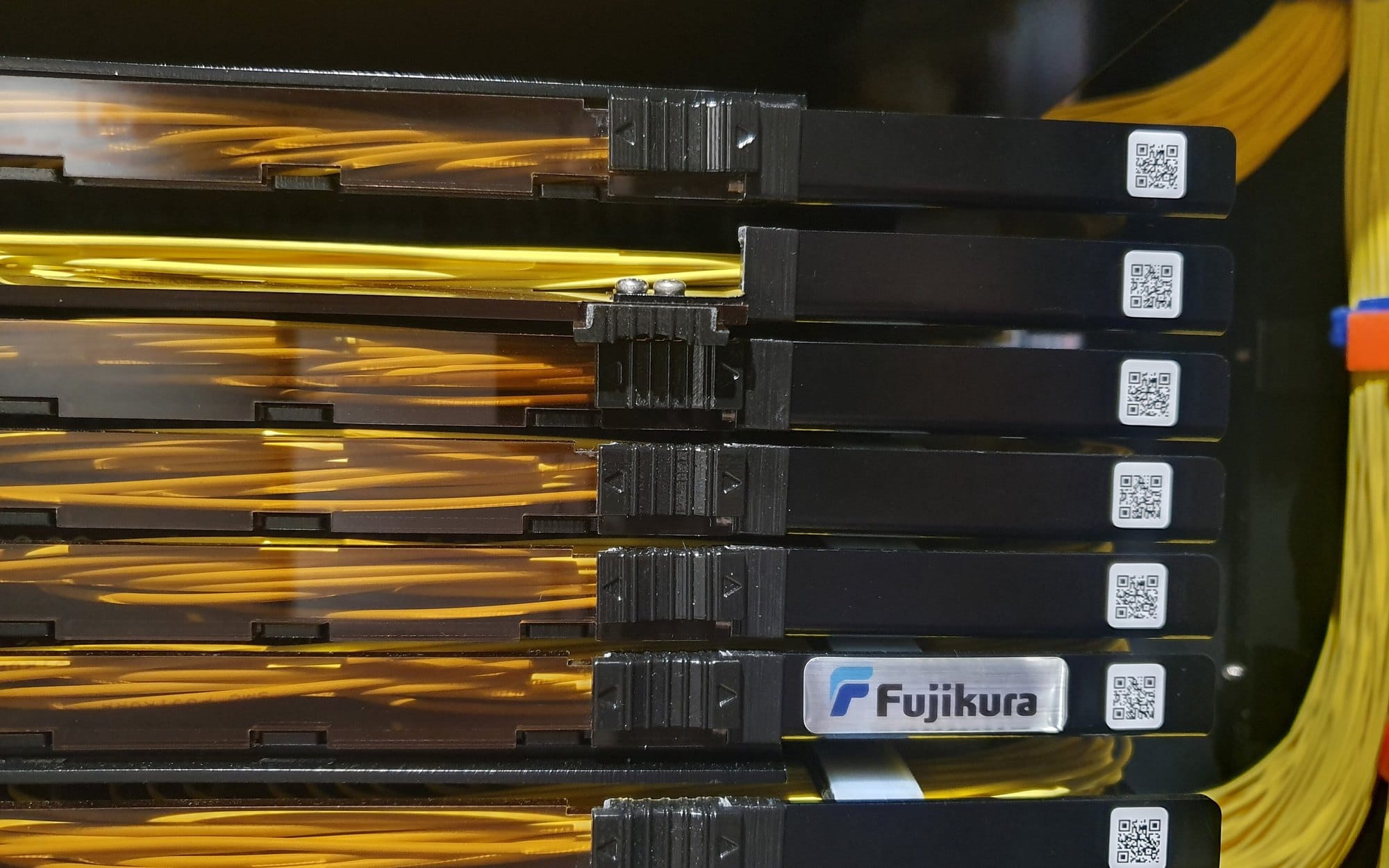 机柜里成排的光纤配线架与黄色光纤跳线